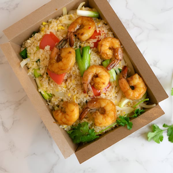 Thai shrimp fried rice with vegetables and cilantro in a brown takeout box.