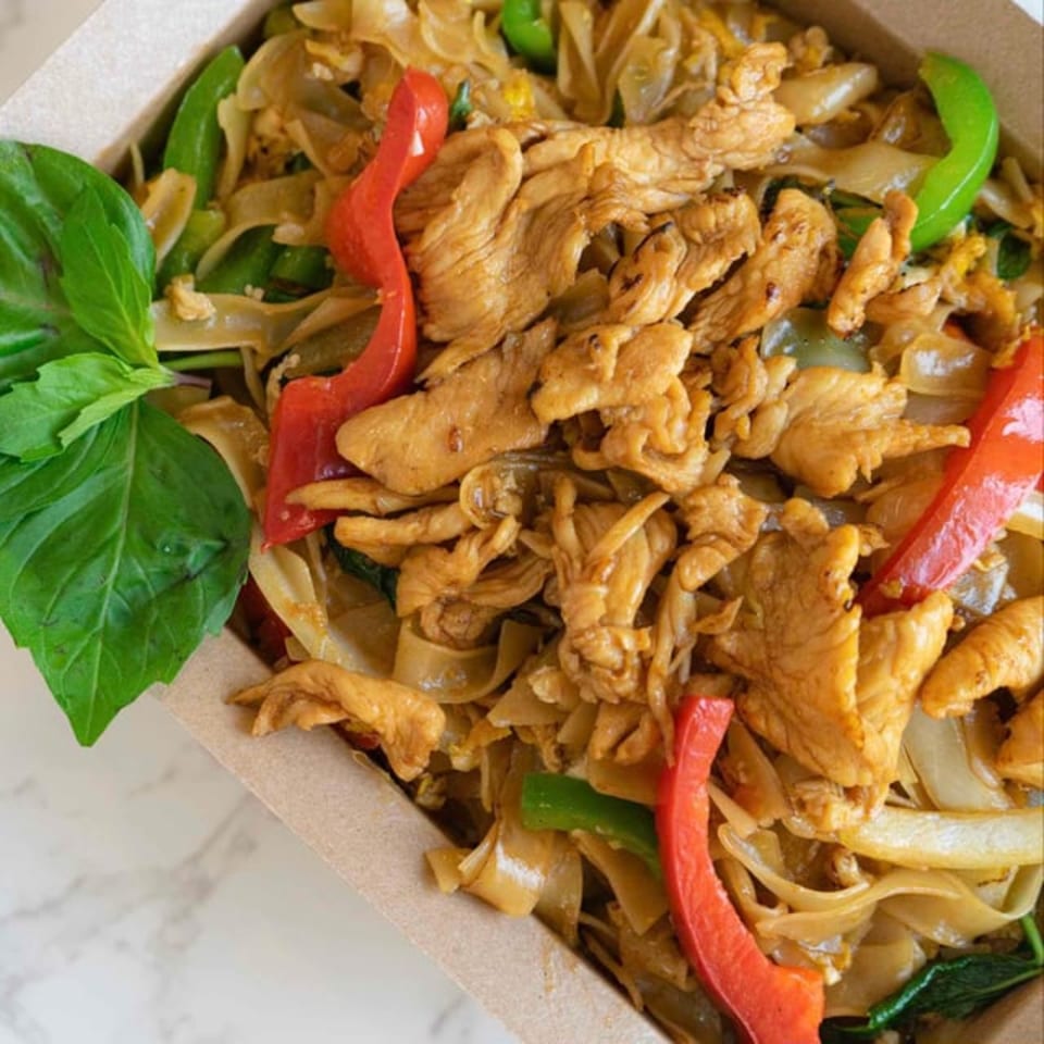 Close-up of Cilantro Thai Express's Pad See Ew with chicken, wide noodles, red and green bell peppers.